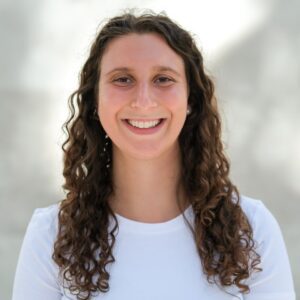 Smiling person with curly hair outdoors.